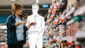Ein Mann und eine Frau stehen vor einem Supermarktregal und sprechen miteinander.